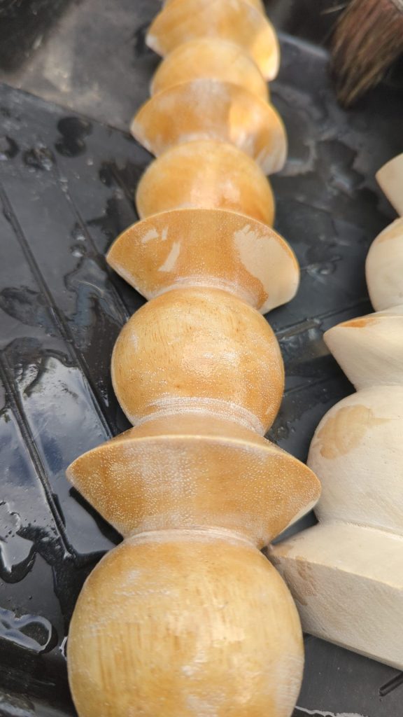 Wooden furniture knobs being stained in shellac close-up showing colour progression