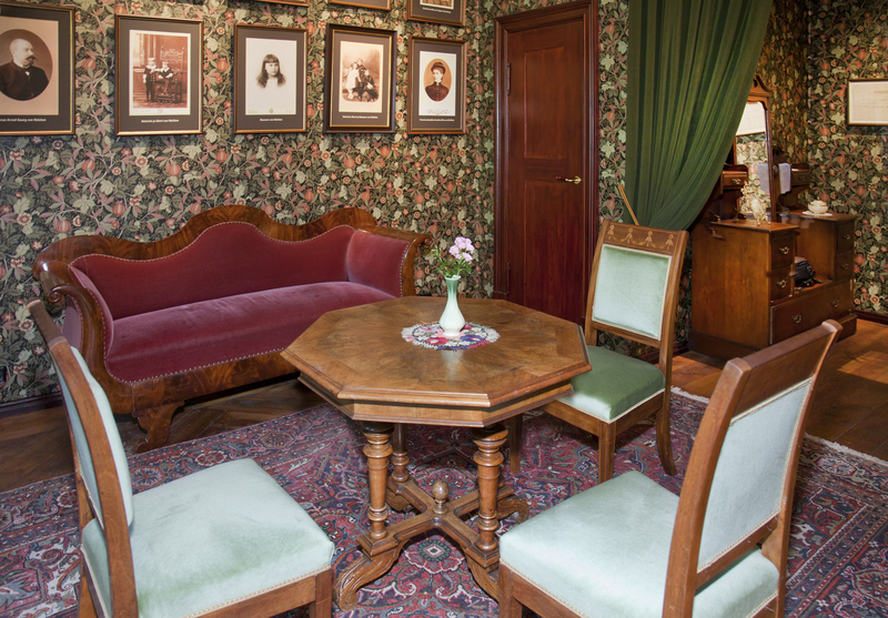 Victorian sitting room with carved mahogany sofa green velvet chairs and ornate octagonal table